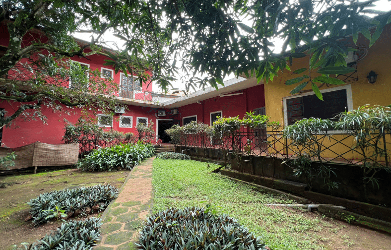 Jardin de l'Hotel Masabi, avec une vue sur l'allée menant au restaurant et aux grandes chambres de l'ancien bâtiment, offrant une atmosphère paisible. Kindia,Guinée