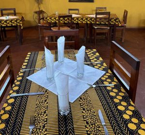 Intérieur chaleureux du restaurant de l'Hotel Masabi à Kindia, Guinée, avec une salle climatisée et une délicieuse sélection de cocktails et plats chauds.